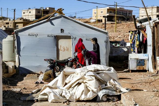 Syrian refugees stand outside a tent about to be dismantled at a camp in Arsal, eastern Lebanon, before returning to Syria