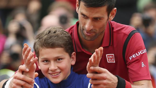 Serbia's Novak Djokovic teaches a ball boy how to celebrate a victory.