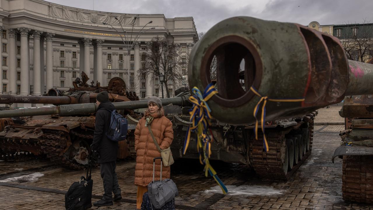 People with their luggage look at destroyed Russian military vehicle on display in Mykhailivskyi Square, in downtown Kyiv, Ukraine. Photo by Roman Pilipey/Getty Images