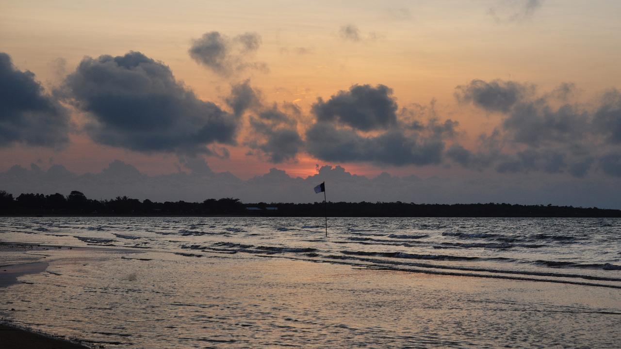 Dawn breaks over Blue Mud Bay, where a sea rights flag can be seen waving at the intertidal mark. Picture: Matt Garrick