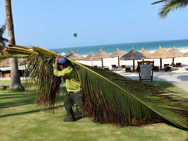 A worker carries coconut tree branches inside a resort in Nha Trang. The first international tourists touched down in Vietnam almost 20 months after the nation closed its borders. Picture: AFP