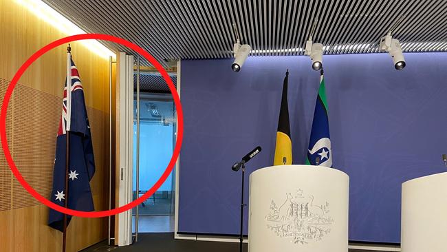 An Australian flag is moved to the side of the room prior to Greens leader Adam Bandt conducting a press conference where he did not want to have the Australian flag and what it symbolises in the camera frame as he spoke.