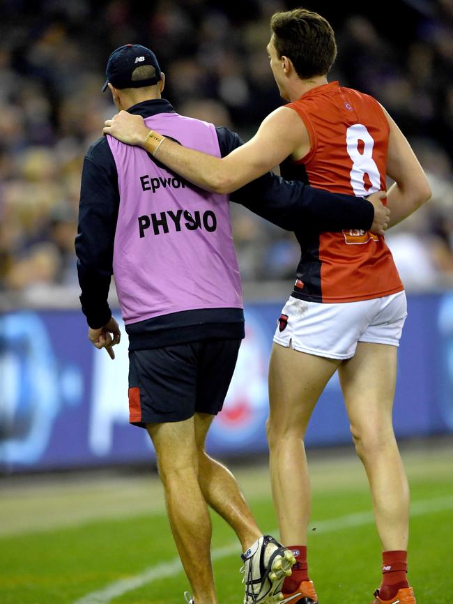 Jake Lever of the Demons is assisted off the ground by a team official against the Western Bulldogs. Picture: AAP Image/Joe Castro