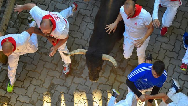 Participants run next to a fighting bull on the sixth bull run of the festival. Picture: AFP