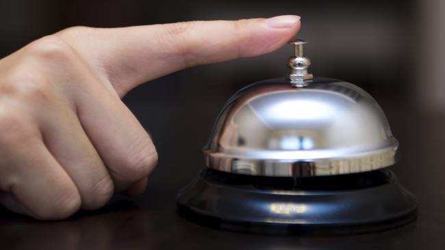 Hand ringing in service bell on wooden table.