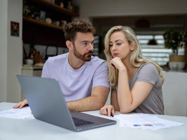 Young couple checking their home finances and looking worried while looking at their bank statements online; money budgeting stress banking generic