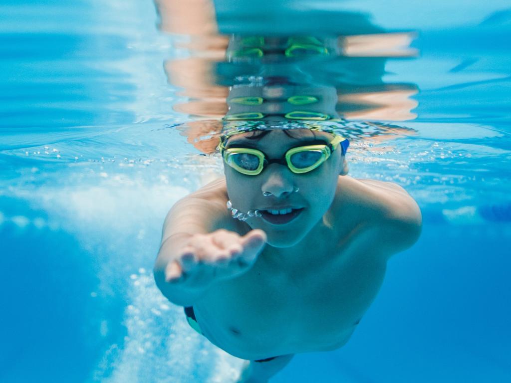 latin child boy swimmer underwater wearing cap and goggles in a swimming training at the Pool in Mexico Latin America