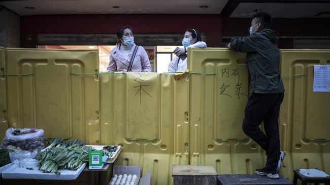 A vendor sells vegetables in front of a makeshift barricade built to control entry and exit to a residential compound in Wuhan. Picture: Getty Images