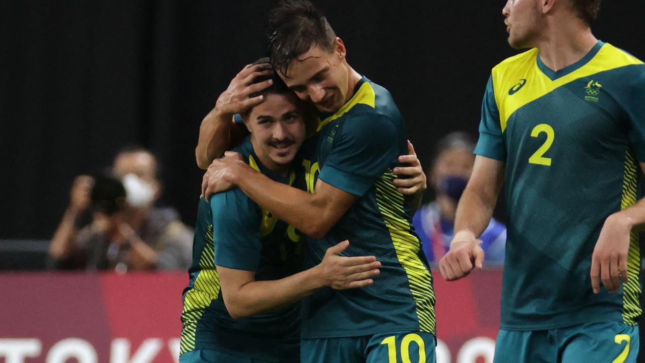 Australia's Marco Tilio (L) celebrates with teammate Australia's midfielder Denis Genreau (C) after scoring during the Tokyo 2020 Olympic Games men's group C first round football match between Argentina and Australia at the Sapporo Dome in Sapporo on July 22, 2021. (Photo by ASANO IKKO / AFP)