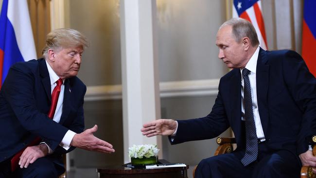 Donald Trump and Vladimir Putin reach to shake hands before a meeting in Helsinki.