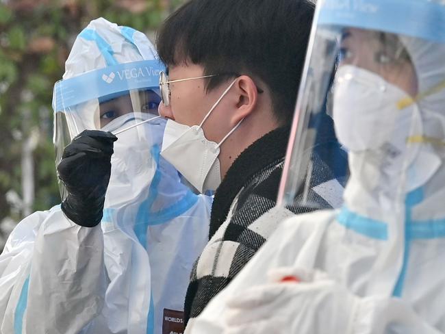 A medical staff (L) wearing protective gear takes samples for the COVID-19 test from a visitor at a testing station in Seoul as cases rise. Picture: AFP