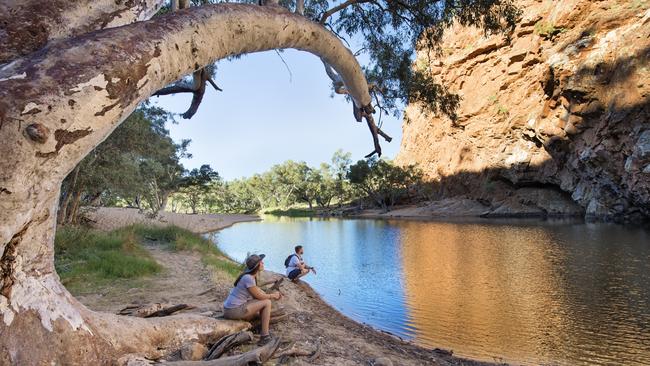 ESCAPE Visitors exploring Ormiston Gorge and Pound. Tjoritja / West MacDonnell National Park stretches for 161 km west of Alice Springs. Explore and appreciate the scenic beauty and history of the area on foot, swim in a waterhole, or pitch a tent for a longer stay. TNT Supplied