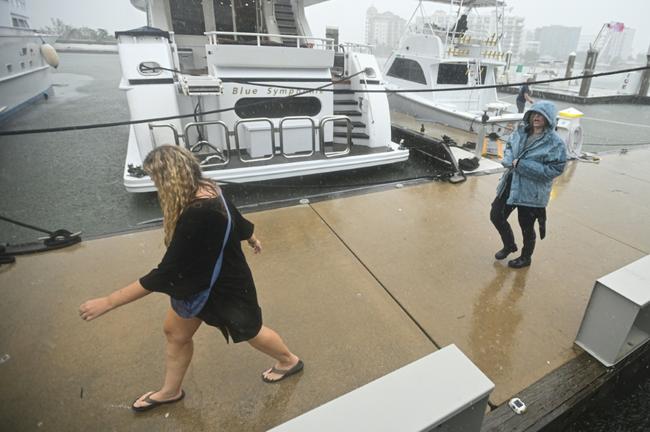 People walk along the marina of Sarasota, Florida as powerful Hurricane Milton nears the coast