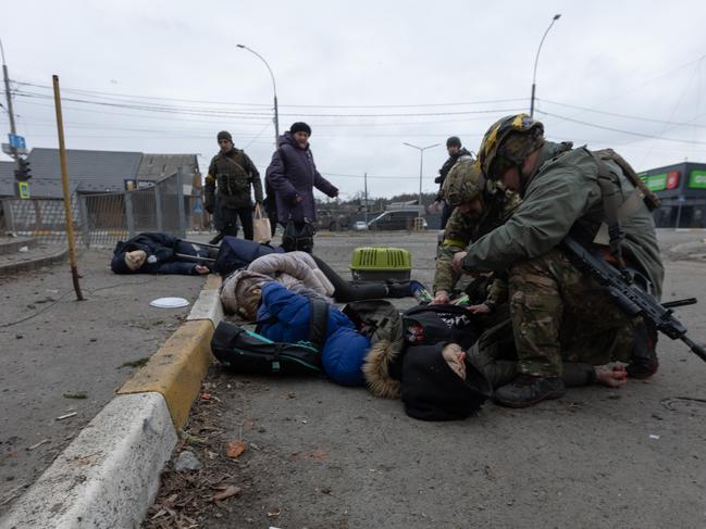 IRPIN, UKRAINE- MARCH 6:  (EDITORS NOTE: Image contains graphic content) Ukrainian soldiers try to aid the victims of a mortar attack from Russian forces on March 6, 2022 in Irpin, Ukraine. At least four died in the attack. Refugees are evacuating toward the capital of Kyiv ahead of advancing Russian forces in Irpin, where according to published reports, refugees in the hundreds are clustered around the damaged bridge over the Irpin River.  (Photo by Andriy Dubchak / dia images via Getty Images)