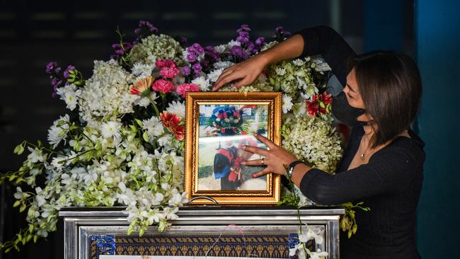 A family member of a victim adjusts a portrait placed atop a coffin as funeral rites begin at the Wat Si Uthai temple. Picture: Getty