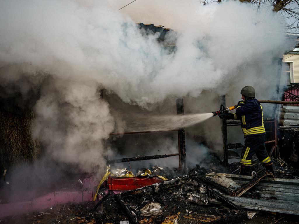 A rescuer extinguishes a fire in a burning shop after Russian shelling to Ukrainian city of Kherson on December 24, 2022, where five were killed and 20 injured. Picture: AFP