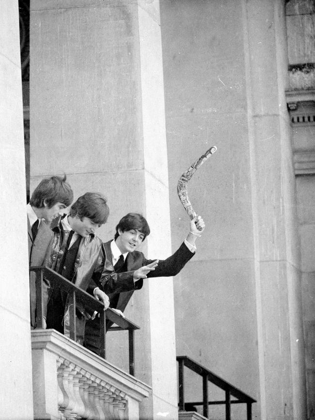 Paul McCartney waves a boomerang from the balcony at the Melbourne Town Hall as the band arrives for a state reception. Picture: Herald Sun Image Library