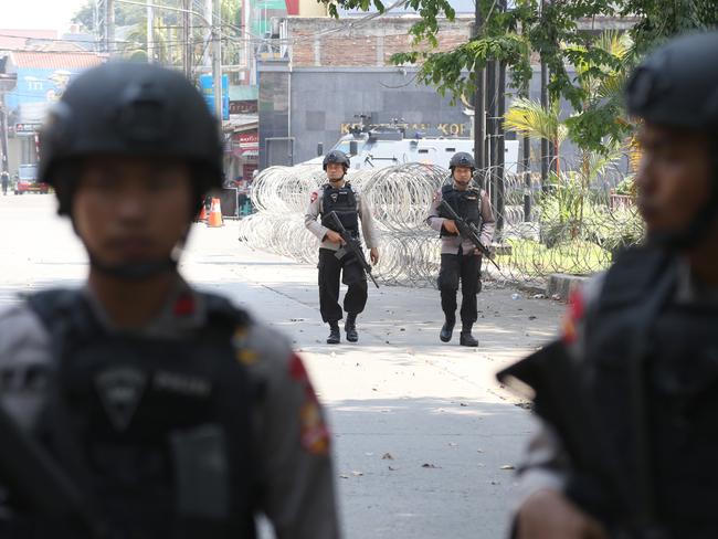 Armed officers walk past roadblock erected outside the headquarters of Mobile Brigade, an elite Indonesian police force, following a riot at the detention centre inside the compound in Depok, West Java. Picture: AP