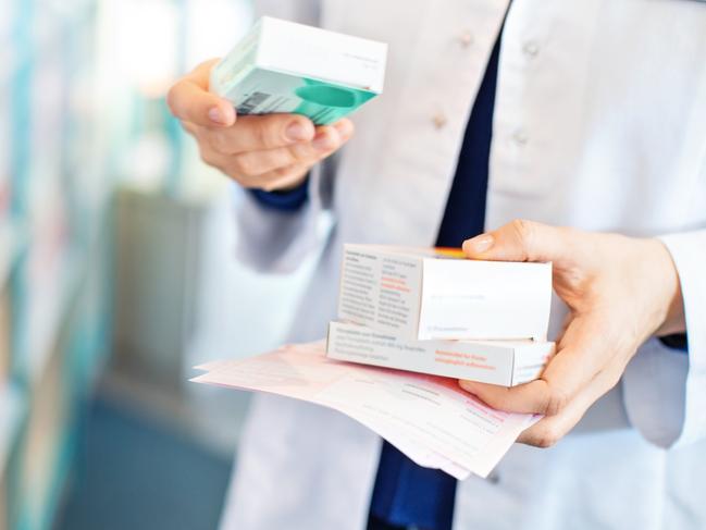 Closeup of pharmacist's hands taking medicines from shelf at the pharmacy