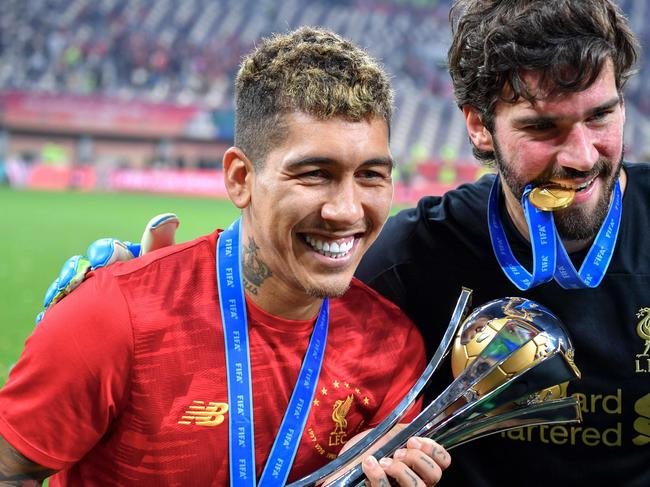 Liverpool's Brazilian midfielder Roberto Firmino (L) and Liverpool's Brazilian goalkeeper Alisson Becker pose with the trophy following the 2019 FIFA Club World Cup Final football match between England's Liverpool and Brazil's Flamengo at the Khalifa International Stadium in the Qatari capital Doha on December 21, 2019. (Photo by Giuseppe CACACE / AFP)