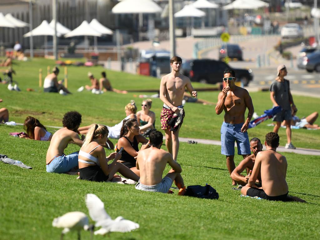 While Bondi Beach is closed and empty the grassed area above is still busy and crowded with people despite social distancing rules. Picture: Joel Carrett/AAP