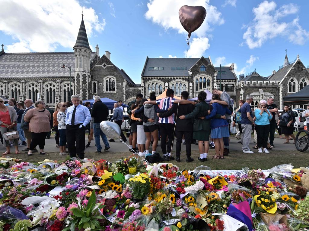 A group of students sings in front of flowers left in tribute to victims at the Botanical Garden in Christchurch. Picture: AFP