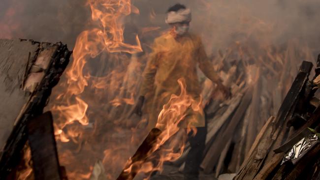 A priest who works at a crematorium is seen amid burning funeral pyres of patients who died of COVID-19 in New Delhi. Picture: Anindito Mukherjee/Getty Images