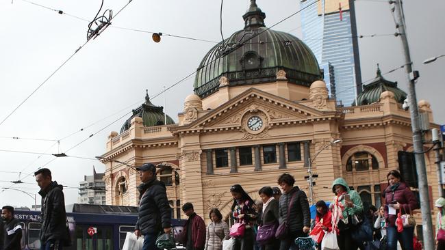 Pedestrians are are seen in wild weather outside Flinders Street Station in Melbourne, Sunday, June 17. 2018. (AAP Image/David Crosling) NO ARCHIVING