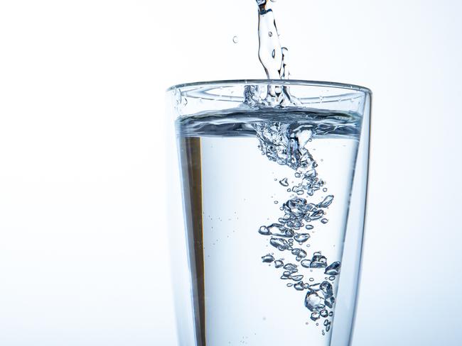 Man filling water from the blue plastic bottle into double glass. Lighting set up shot on white background. Concept of good health and refreshment.