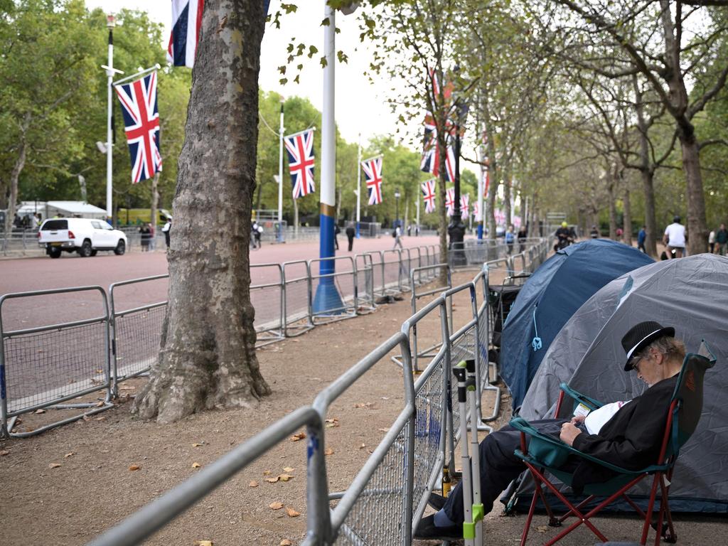 A person sits next to tents pitched along The Mall, leading to Buckingham Palace. Picture: AFP