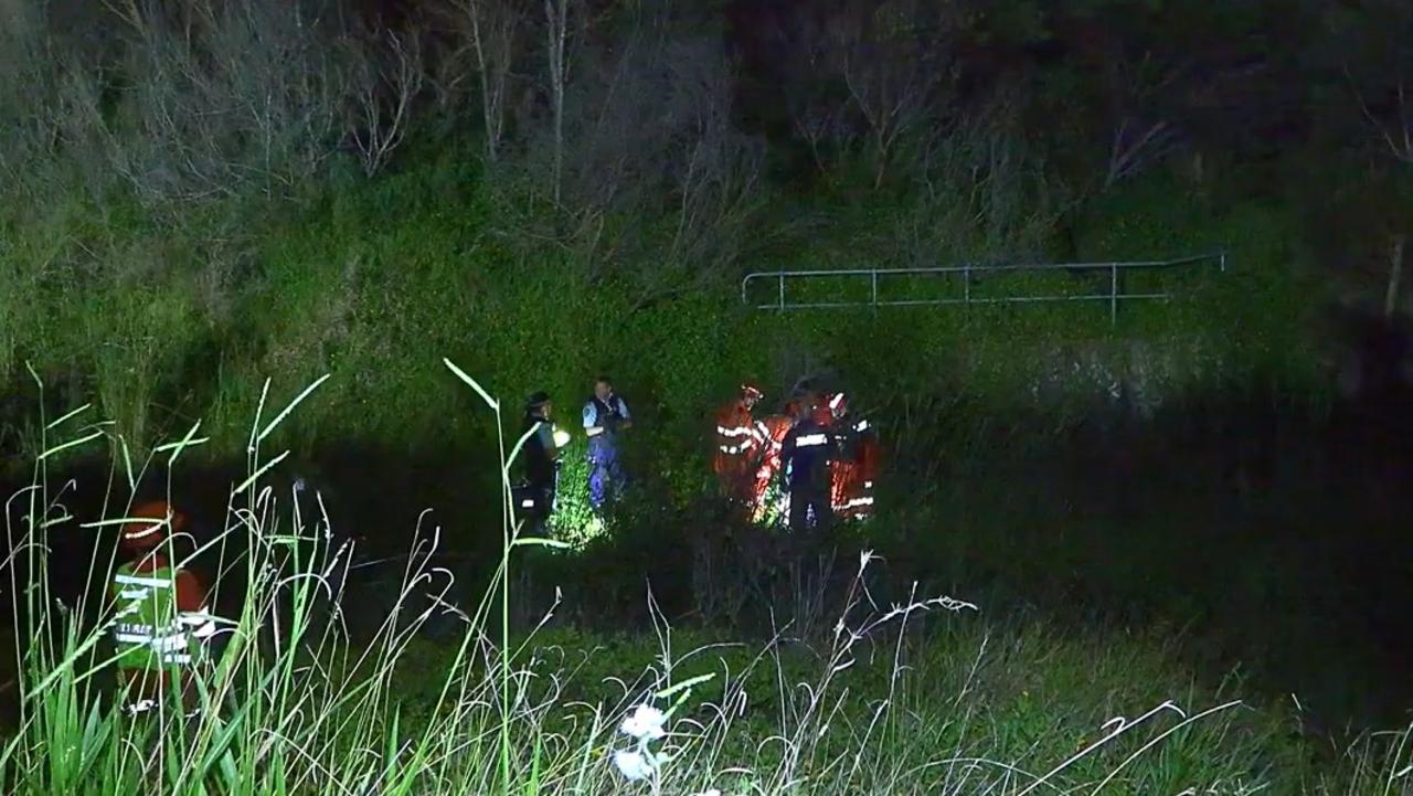 Emergency service workers help a man after a crash that happened in an exit lane from the Pacific Highway at Moonee Beach on March 9, 2022.