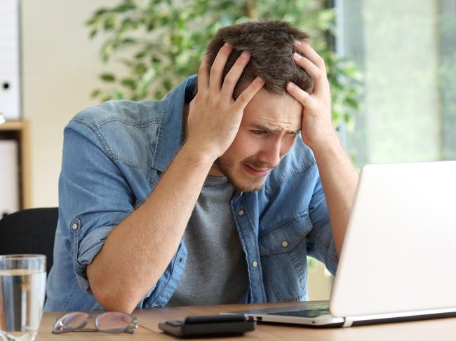 A stressed man at his computer after just realising he has been scammed. Picture: iStock.