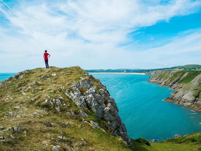 ESCAPE -  Best edition, October 23, Bucketlist Travel -  Woman in red shirt gazing on top of the rocky cliffs in South Gower, Wales, UK. To find these cliffs follow the hiking path between Three Cliffs Bay and Caswell Bay in South Gower, Wales.  Picture: Istock