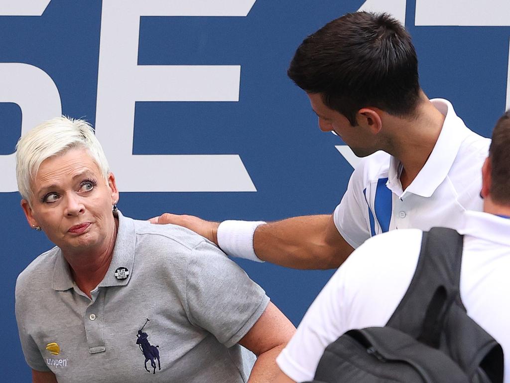 Novak Djokovic of Serbia tends to a line judge who was hit with the ball.