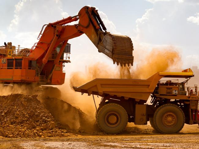 A haul truck is loaded by a digger with material from the pit at Rio Tinto Group's West Angelas iron ore mine in Pilbara, Australia, on Sunday, Feb. 19, 2012. Rio Tinto Group, the world's second-biggest iron ore exporter, will spend $518 million on the first driverless long-distance trains to haul the commodity from its Western Australia mines to ports, boosting efficiency. Photographer: Ian Waldie/Bloomberg via Getty Images