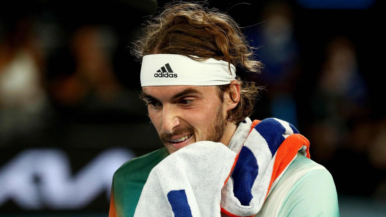 Greece's Stefanos Tsitsipas wipes his face while playing against Russia's Daniil Medvedev during their men's singles semi-final match on day twelve of the Australian Open tennis tournament in Melbourne on January 28, 2022. (Photo by Aaron FRANCIS / AFP) / -- IMAGE RESTRICTED TO EDITORIAL USE - STRICTLY NO COMMERCIAL USE --