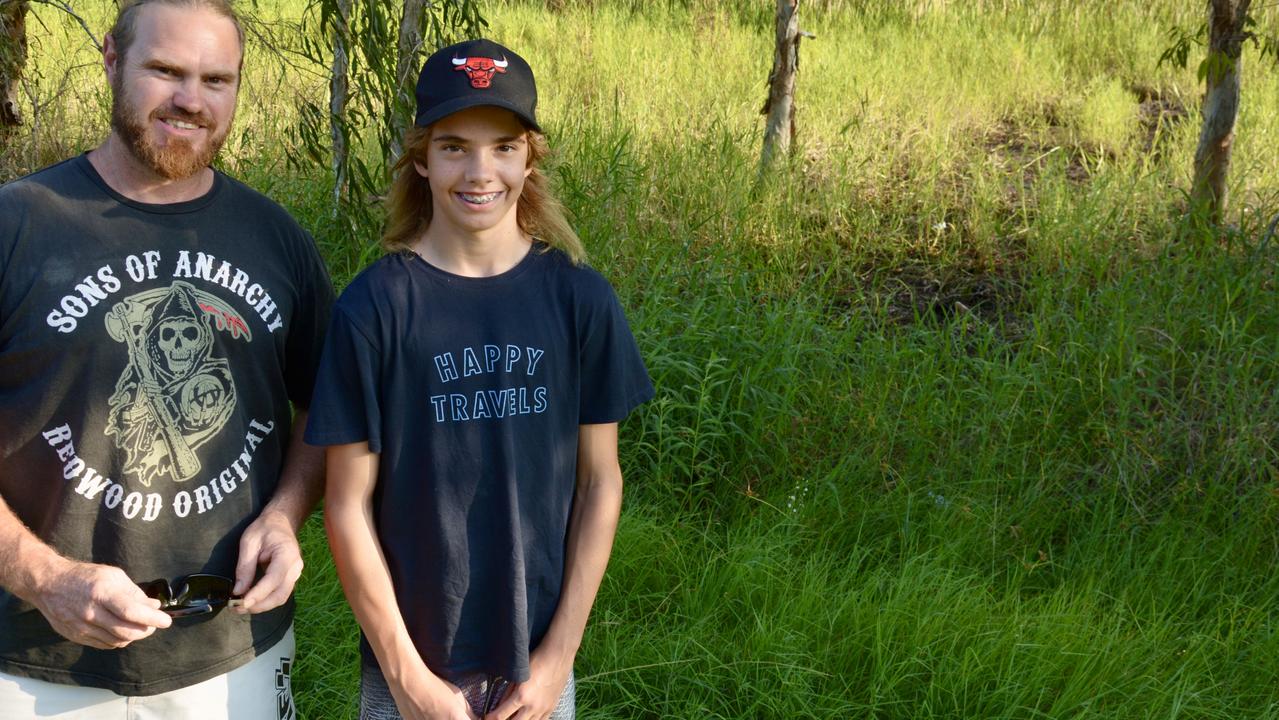 Clint Barker and his son Dayne were on the way to the Bucasia IGA when they spotted a crocodile crossing the road. They watched it go back into the swamp land pictured behind them on Hennessy St at Bucasia. They believe the flattened grass is a regular path for the crocodile. Picture: Rae Wilson