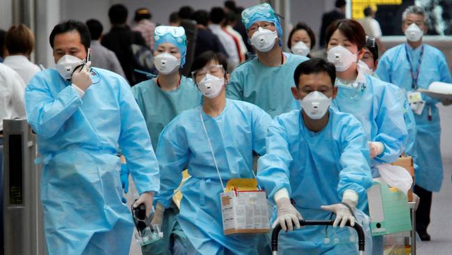 Quarantine officials with protective masks and outfits make their way to board a commercial plane that has just arrived for checking of its passengers at Narita International Airport in Narita, east of Tokyo, Japan, Sunday, May 10, 2009. Japan confirmed that a fourth person had swine flu Sunday, a day after the nation's first cases were found, the health ministry said. (AP Photo/Itsuo Inouye)