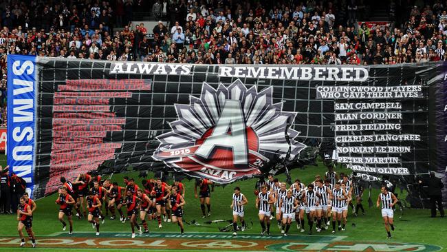 The two teams run through a tribute banner side-by-side on Anzac Day.