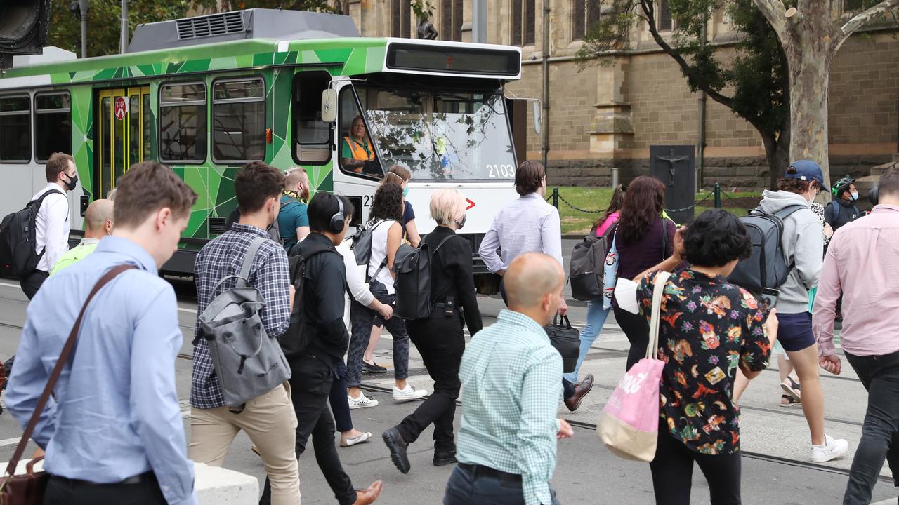 Workers cross Swanston St on Monday. Picture: David Crosling