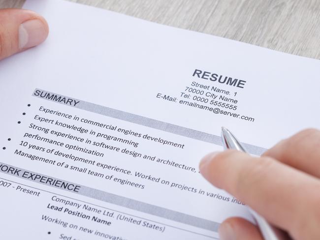 Close-up Of Businessman Reading Resume With Tea Cup On Desk