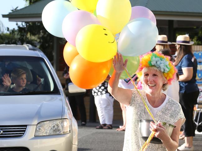 Teachers at Emmanual College line up to wave at their students and hand out lollies at a drive  through the pick-uip drop off zone designed to let the kids know they're missed. Junior School Deputy dressed up for the occassion (wig and balloons) and handed out lollies.  Picture Glenn Hampson