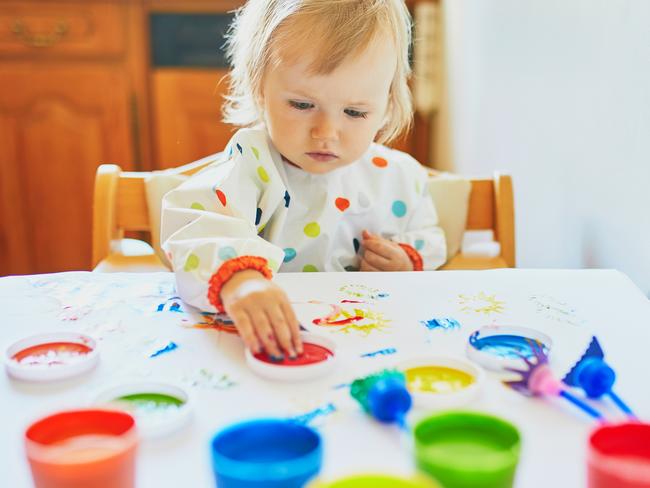 Adorable little girl painting with fingers at home, in kindergaten or preschool. Creative games for kids