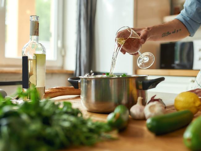 EMBARGO FOR TWAM 29 JAN 2022. FEES MAY APPLY.  Cropped shot of man, chef cook pouring a glass of white wine into the pan with chopped vegetables while preparing a meal in the kitchen. Cooking at home, Italian cuisine. Selective focus. Web Banner