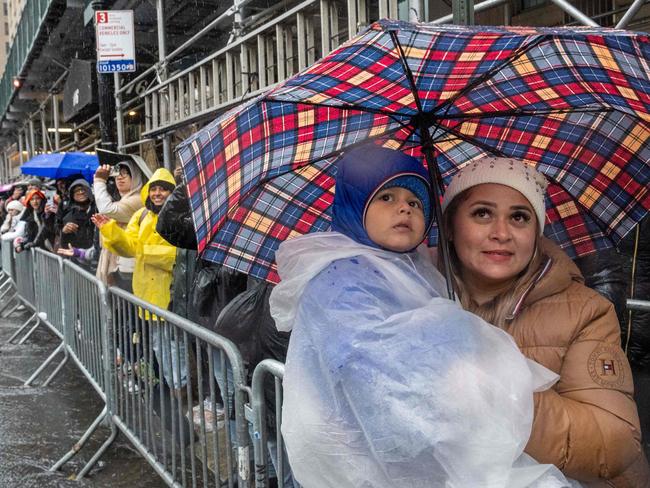 People stand under umbrellas as they watch the procession of balloons during the annual Macy's Thanksgiving Day Parade. Picture: AFP