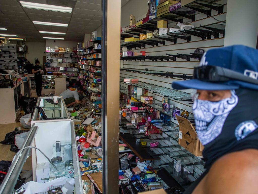 A man wearing a face cover looks at a looted store in downtown Long Beach. Picture: Apu Gomes/AFP