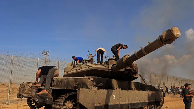 Palestinians take control of an Israeli tank after crossing the border fence with Israel from Khan Yunis in the southern Gaza Strip. Picture: AFP