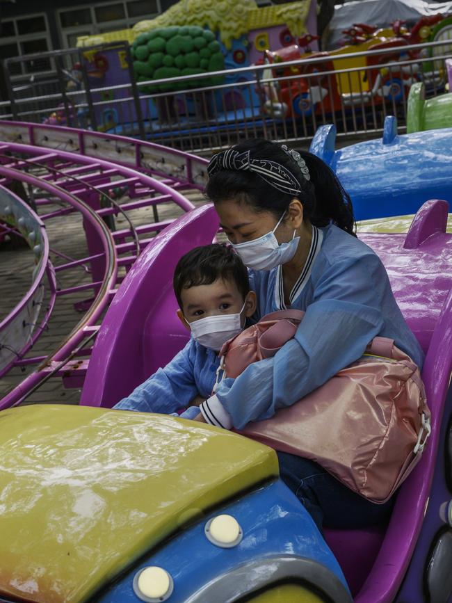 A Chinese woman and boy wear protective masks as they enjoy a ride at a small amusement area during the country’s May holiday. Picture: Kevin Frayer/Getty Images