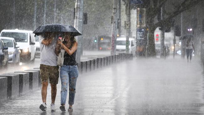 A couple caught in the heavy downpour that hit Melbourne on Friday afternoon. Picture: David Caird