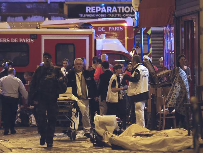 Chaos ... Police officers and rescue workers gather around a victim outside in the 10th district of Paris. Picture: AP Photo/Jacques Brinon